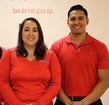 This is a picture of three employees on the far left side is alady with brown hair and a orange shirt, the lady in the middle has brown hair with a orange shirt and to the far right is a male with brown hair and a orange polo shirt on.